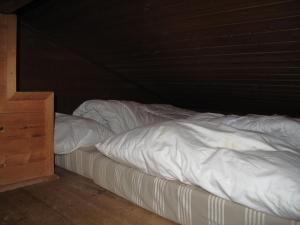 1 cama no hecha con sábanas blancas y armario de madera en Chalet Hüttl by Interhome en Trins