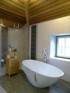 eine große weiße Badewanne im Bad mit Fenster in der Unterkunft La grange à Tissac in Cazes-Mondenard