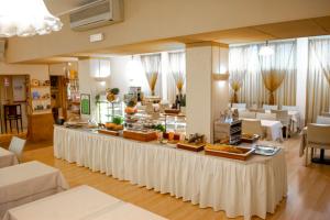 un buffet en un restaurante con mesas y sillas blancas en eco Hotel Milano & BioRiso Restaurant en Milán