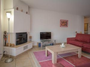 een woonkamer met een rode bank en een open haard bij Apartment La Rèze No 6 by Interhome in Ovronnaz