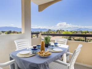 a dining table with a blue table cloth and white chairs at Apartment Les Capitelles by Interhome in Saint-Cyprien-Plage