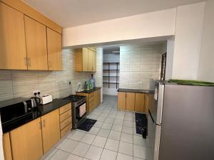 a kitchen with wooden cabinets and a stainless steel refrigerator at Nyachaba Apartment in Kisumu