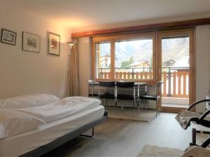 1 dormitorio con cama, mesa y balcón en Studio Silence-4 by Interhome, en Zermatt