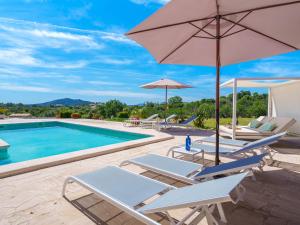 a group of chairs and umbrellas next to a swimming pool at Holiday Home Es Cos by Interhome in Moscari