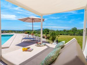 eine Terrasse mit einem Sofa, einem Sonnenschirm und einem Pool in der Unterkunft Holiday Home Es Cos by Interhome in Moscari