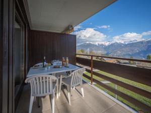 a table and chairs on a balcony with a view of mountains at Apartment Austral 204 by Interhome in Ovronnaz