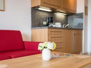 a vase of flowers on a table with a red couch at Apartment A410 by Interhome in Lahnstein