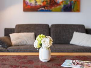a white vase with flowers on a table in a living room at Apartment A706 by Interhome in Lahnstein