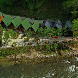 Çamlıhemşin的住宿－Tanura Bungalows，河边的绿色屋顶建筑