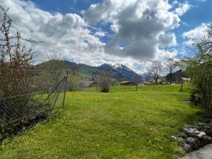 a field with a fence and mountains in the background at Apartment Akelei - klein by Interhome in Zweisimmen