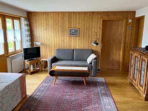 a living room with a couch and a tv at Apartment Akelei - klein by Interhome in Zweisimmen