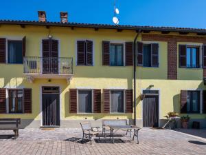 een gebouw met twee stoelen en een tafel ervoor bij Holiday Home Agriturismo I Tre Tigli by Interhome in Serravalle dʼAsti