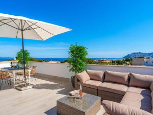 eine Terrasse mit einem Sofa und einem Tisch mit einem Sonnenschirm in der Unterkunft Villa Can Aruna by Interhome in Colònia de Sant Pere