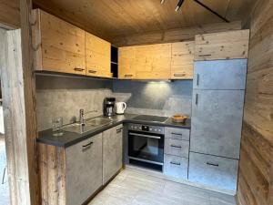 una pequeña cocina con armarios de madera y nevera. en Apartment Eberharter - ZAZ692 by Interhome, en Aschau