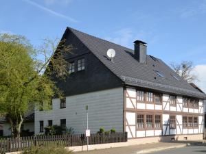 a white and brown building with a black roof at Apartment An der Dorfkirche by Interhome in Hohe