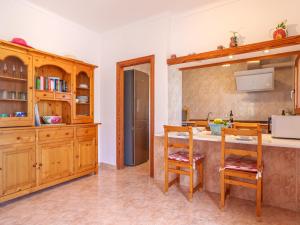 una cocina con armarios de madera y una encimera con 2 sillas en Apartment - SNY160 by Interhome, en Cala Santanyi