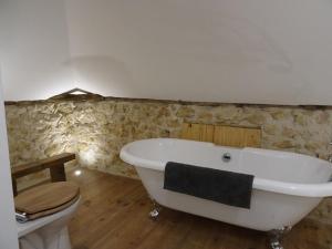 y baño con bañera blanca y aseo. en Le Moulin du Clapier La Banette, en Sorges