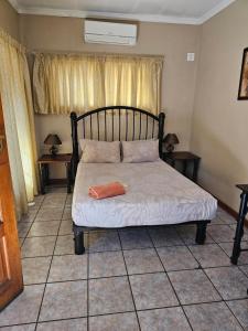 a bed in a room with two tables and a window at Motel Villa Africa in Polokwane