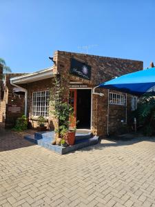 a brick building with a blue umbrella in front of it at Motel Villa Africa in Polokwane
