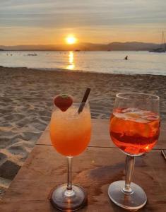 two drinks sitting on a wooden table on the beach at Appartement Pearl Beach in Saint-Tropez