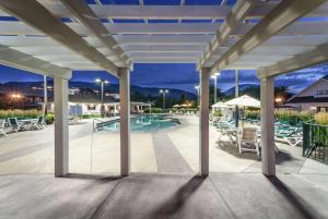 a patio with a pool and tables and chairs at Balcomo, a Ramada by Wyndham in Penticton