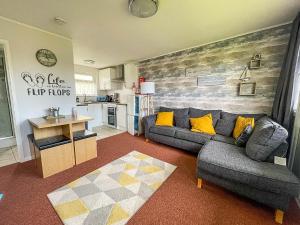 a living room with a couch and a kitchen at Beautiful Chalet With Free Wifi Nearby Hemsby Beach In Norfolk Ref 59096s in Hemsby