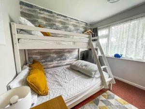 a bedroom with a bunk bed with a ladder at Beautiful Chalet With Free Wifi Nearby Hemsby Beach In Norfolk Ref 59096s in Hemsby