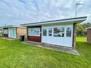 a small house with a garage in a yard at Beautiful Chalet With Free Wifi Nearby Hemsby Beach In Norfolk Ref 59096s in Hemsby