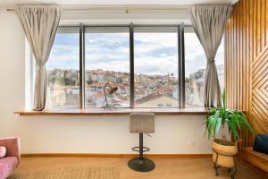 - un salon avec une grande fenêtre et une chaise dans l'établissement Coimbra Premium Downtown, à Coimbra