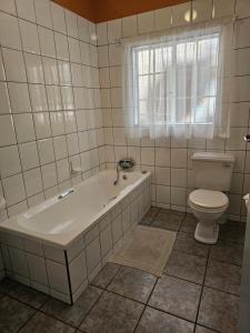 une salle de bain blanche avec une baignoire et des toilettes dans l'établissement Motel Villa Africa, à Polokwane 10 autres photos