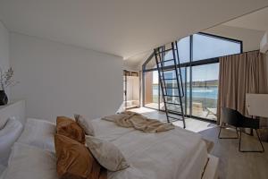 a bedroom with a white bed and a ladder at Vanduo Marse in Tuliejai