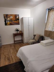 a bedroom with a white bed and a chair at Quality space in Havering atte Bower