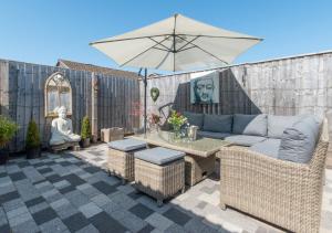 a patio with a couch and a table with an umbrella at 5 The Fairway in Braunton