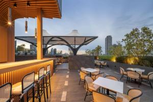 a restaurant with tables and chairs on a rooftop patio at Ramada Plaza by Wyndham Bangkok Sukhumvit 48 in Bangkok