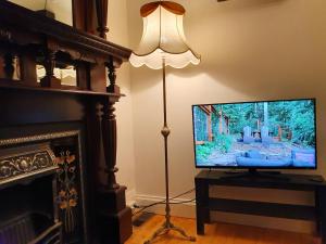 sala de estar con lámpara de pie y TV de pantalla plana en Outstanding property Close to Melb Airport, en Melbourne