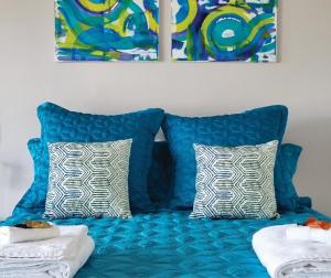 a blue couch with two pillows and two paintings at 1-bedroom unit with balcony and ocean views! in Smiths Beach