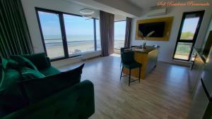 a living room with a couch and a television and the beach at Sofi Residence Promenada in Mamaia Nord