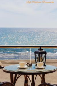 Sofi Residence Promenada في مامايا نورد نافورداي: طاولة مع كوبين ومصباح على الشاطئ