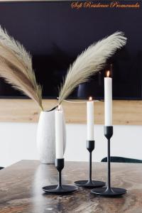 two candles sitting on top of a table with a vase at Sofi Residence Promenada in Mamaia Nord