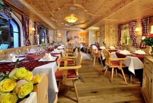 un restaurante con mesas y sillas con rosas amarillas en Wellnesshotel Mitterwirt, en Dienten am Hochkönig