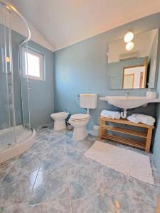 y baño con 2 aseos, lavamanos y ducha. en Villa Porto en Rogač