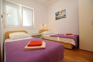 席洛的住宿－Apartmani Zec，客房设有两张带紫色床单的床和窗户。