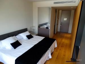 1 dormitorio con 1 cama grande con almohadas blancas y negras en Blu Hotel Almansa, en Almansa