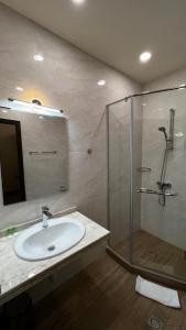 Olympia Garden Hotel في يريفان: حمام مع حوض ودش زجاجي