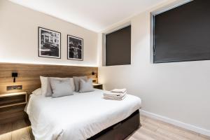 ein Schlafzimmer mit einem Bett und zwei Fenstern in der Unterkunft Exclusive Apartments Barcelona 4 personas G Humet in Terrassa