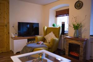 a living room with a tv and a chair and a fireplace at Ferienwohnung Zum Jehöschnis in Gerolstein