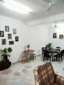 ein Wohnzimmer mit Tischen und Stühlen und einer weißen Wand in der Unterkunft 88 Homestay Teluk Intan 5 minutes to Leaning Tower in Teluk Intan