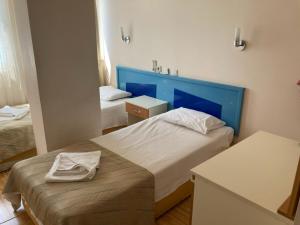 a small bedroom with two beds and a blue headboard at Er-Öz Hotel in Fethiye