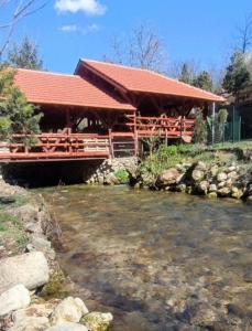 a building with a red roof next to a river at ŽUBOR VRELA in Despotovac