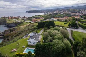 una vista aerea di una casa su una collina vicino all'acqua di Impresionante villa sobre el mar en el mismo Comillas a Comillas